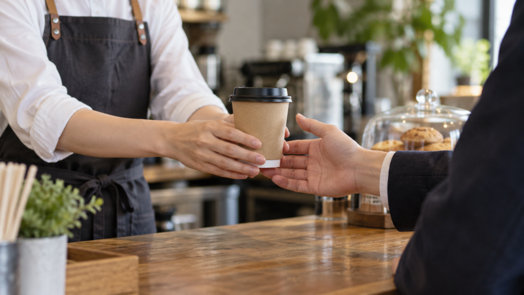 カフェで飲み物を受け渡すスタッフと顧客のイメージ